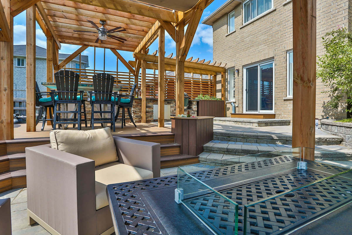 Backyard home design with natural wood, seating, large patio, pool and stainless steel appliances.