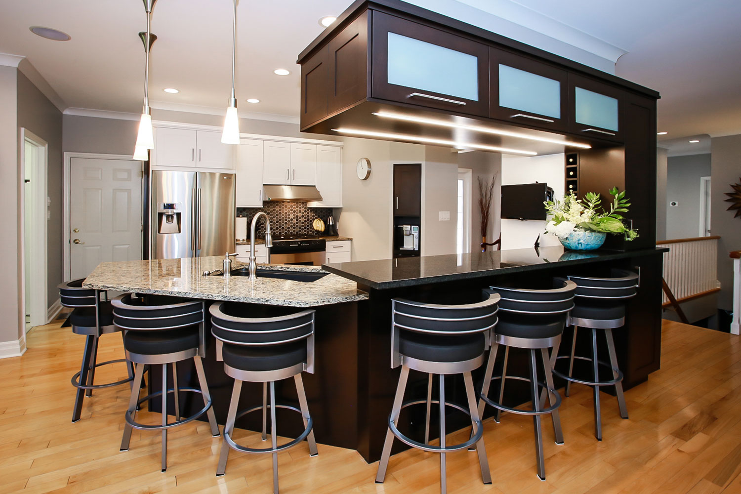 Contemporary kitchen with white and dark wood cabinets featuring a dual height island, stainless steel appliances, built-in cappucino machine and wine shelf - Total Living Concepts