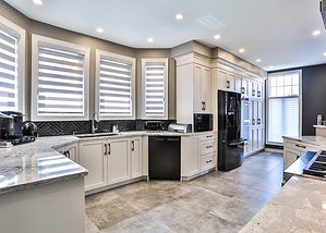 White kitchen design with a large island, white cupboards, and tile floors.